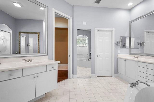 bathroom featuring tile patterned floors, vanity, and a washtub