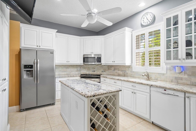 kitchen featuring white cabinets, light tile patterned floors, a textured ceiling, and stainless steel appliances