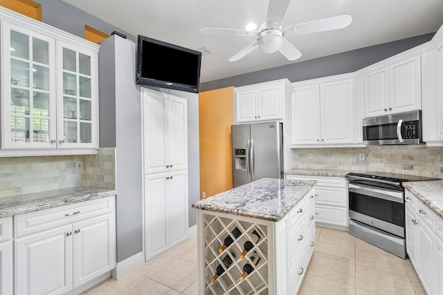 kitchen with white cabinets, light tile patterned flooring, light stone counters, and stainless steel appliances