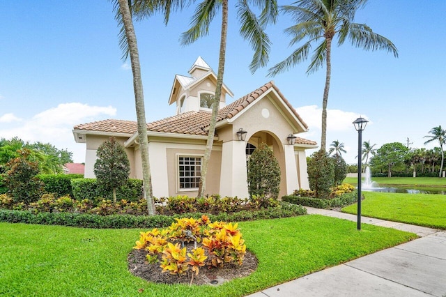 mediterranean / spanish-style house with a front yard and a water view