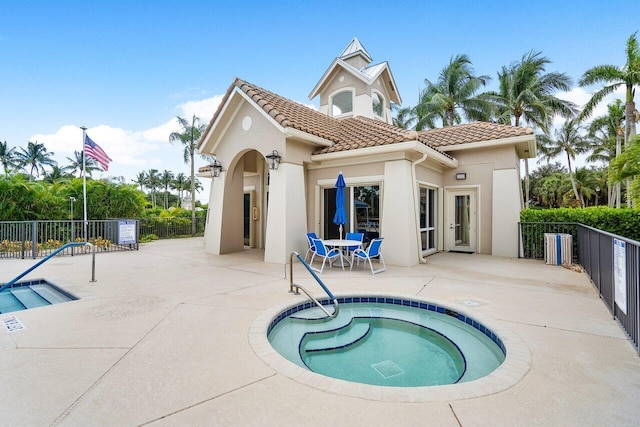 rear view of property with a community hot tub and a patio area