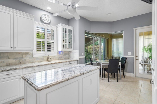 kitchen with tasteful backsplash, white cabinetry, and light stone counters