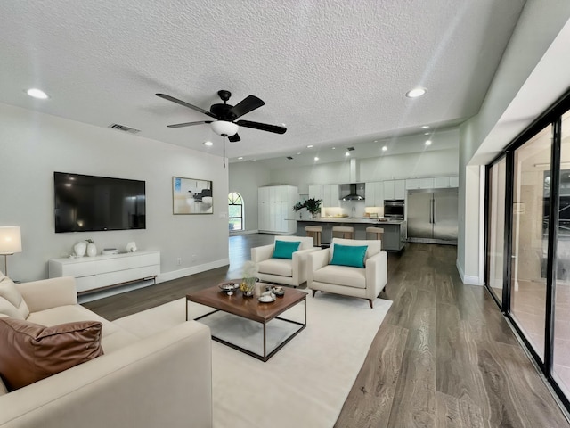 living room featuring ceiling fan, light hardwood / wood-style floors, and a textured ceiling