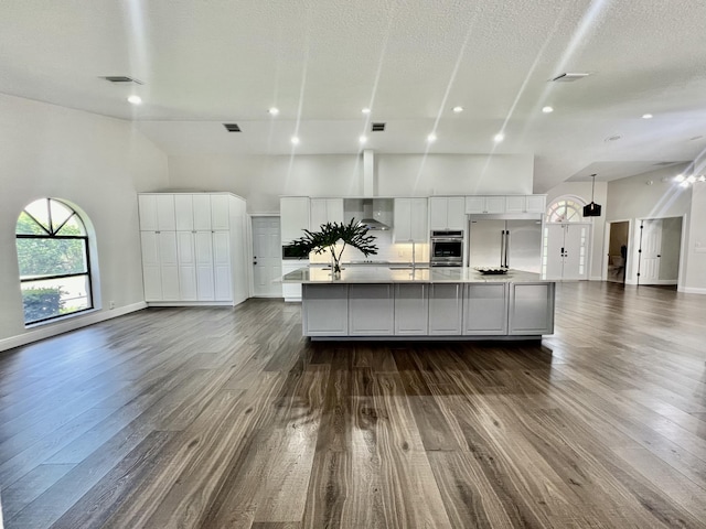 kitchen with stainless steel appliances, a towering ceiling, white cabinets, and a spacious island