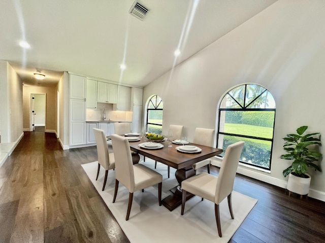 dining room featuring dark hardwood / wood-style floors, a towering ceiling, and sink