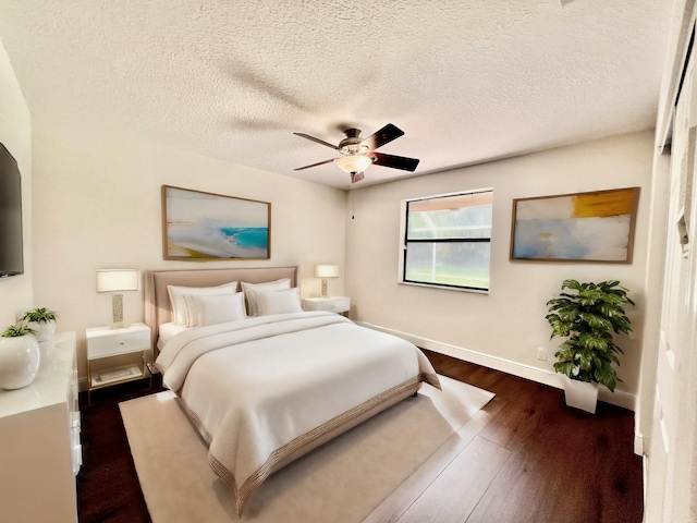 bedroom with a textured ceiling, ceiling fan, and dark wood-type flooring