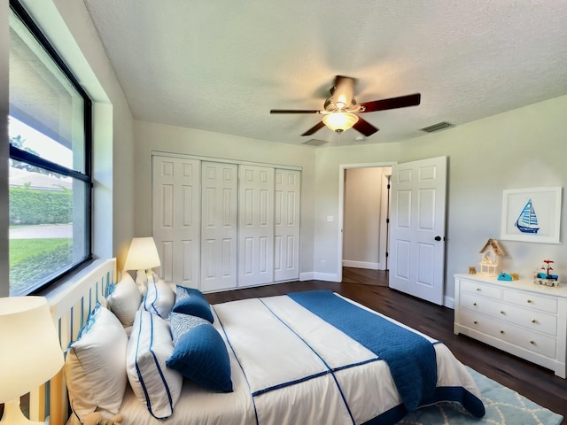 bedroom with ceiling fan, dark hardwood / wood-style floors, a textured ceiling, and a closet