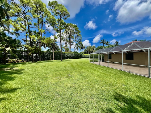 view of yard with glass enclosure and a patio area