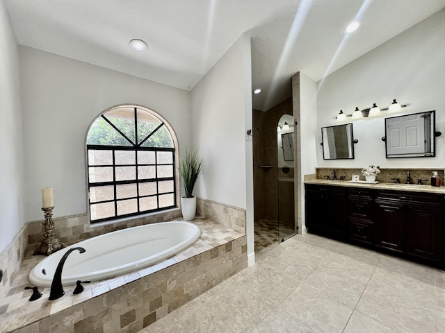 bathroom featuring tile patterned floors, vanity, separate shower and tub, and vaulted ceiling