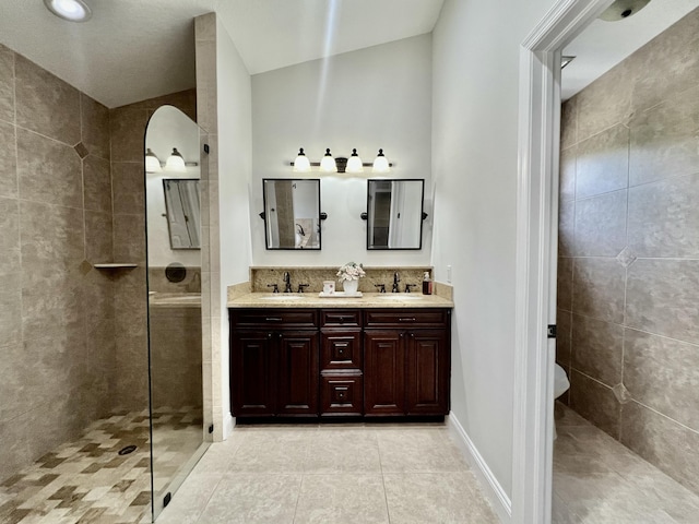 bathroom featuring tile patterned flooring, a tile shower, vanity, and lofted ceiling