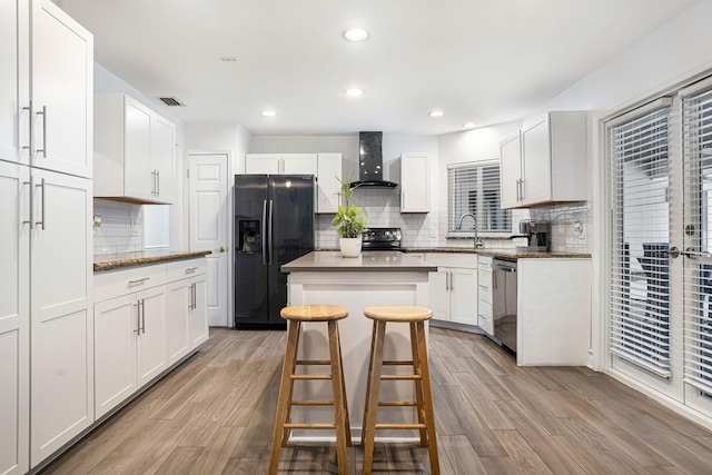 kitchen featuring appliances with stainless steel finishes, wall chimney exhaust hood, a breakfast bar, a center island, and white cabinetry