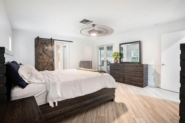 bedroom featuring a barn door, light wood-type flooring, and access to outside