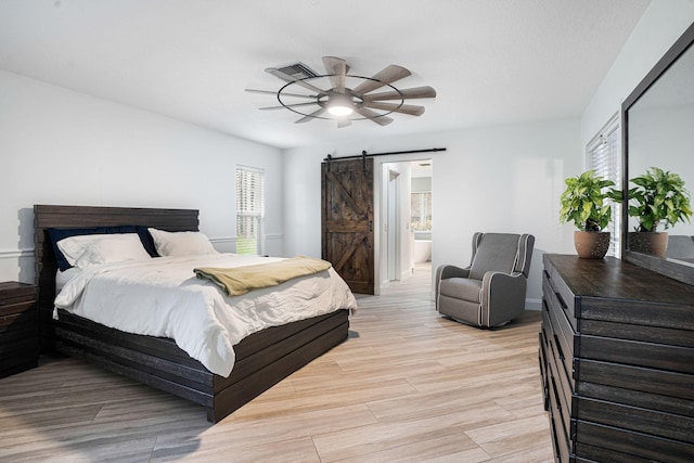 bedroom featuring ceiling fan, a barn door, and ensuite bath