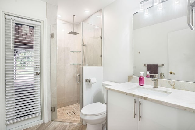 bathroom featuring wood-type flooring, vanity, toilet, and a shower with door