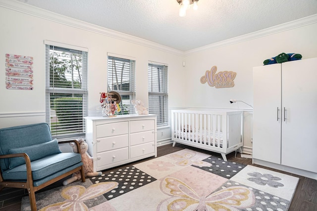 bedroom with a textured ceiling, dark hardwood / wood-style floors, a nursery area, and crown molding