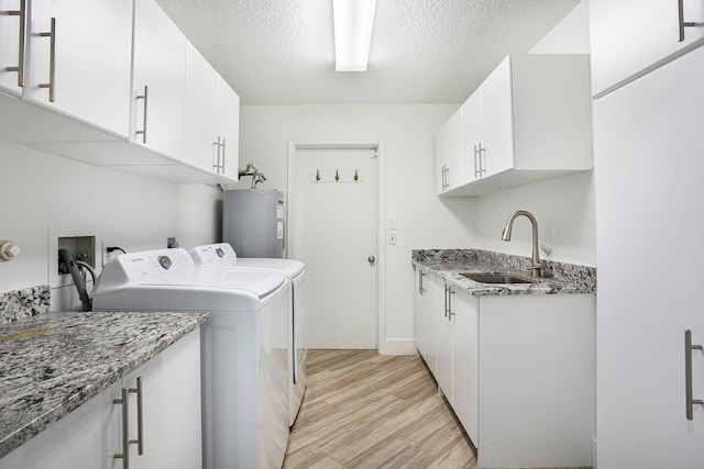 laundry room featuring light wood-type flooring, a textured ceiling, sink, water heater, and independent washer and dryer