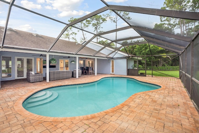 view of swimming pool featuring glass enclosure, ceiling fan, and a patio