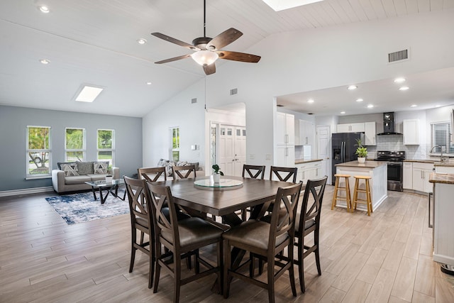 dining area with lofted ceiling with skylight, ceiling fan, sink, light hardwood / wood-style flooring, and wooden ceiling