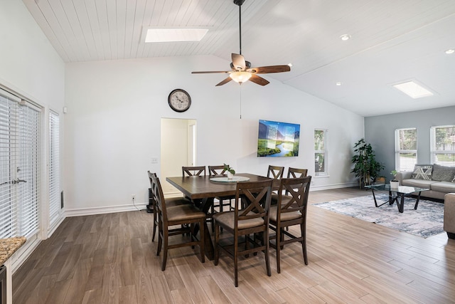 dining room with ceiling fan, light wood-type flooring, wood ceiling, and lofted ceiling with skylight