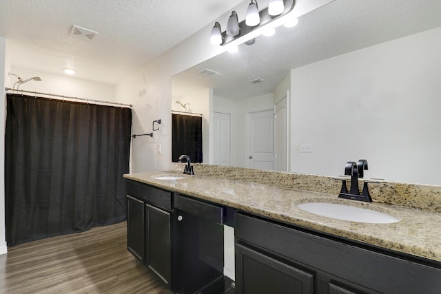 bathroom with hardwood / wood-style flooring, vanity, a textured ceiling, and walk in shower