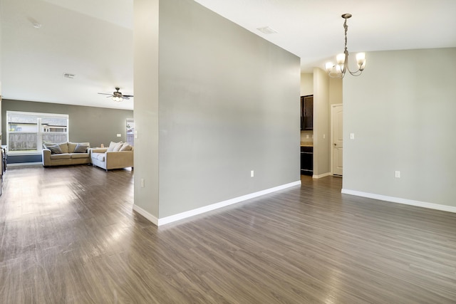 empty room with ceiling fan with notable chandelier and dark hardwood / wood-style flooring