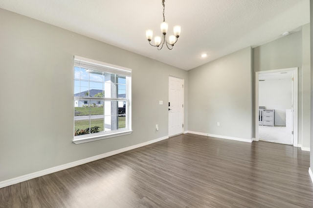 spare room featuring dark hardwood / wood-style flooring and an inviting chandelier