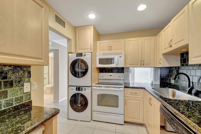 kitchen featuring sink, white appliances, stacked washer / drying machine, and light tile patterned flooring