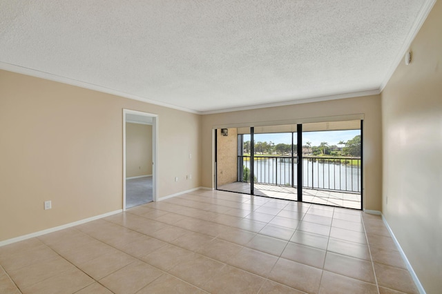 tiled empty room featuring ornamental molding, a textured ceiling, and a water view