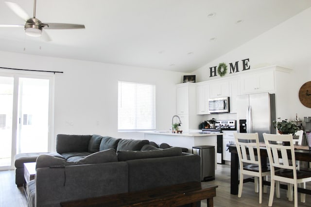 living room featuring ceiling fan, plenty of natural light, dark wood-type flooring, and vaulted ceiling