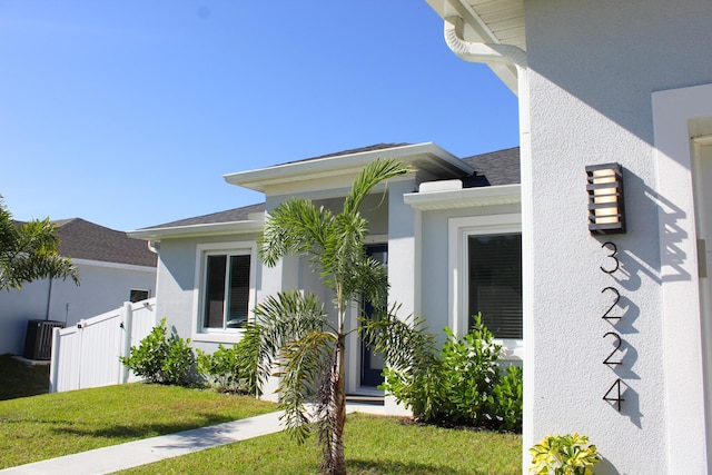 entrance to property with central air condition unit and a yard