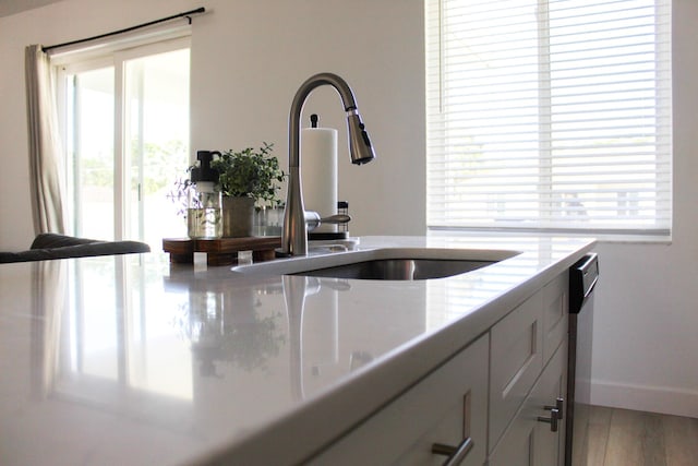 kitchen featuring stainless steel dishwasher, light hardwood / wood-style floors, white cabinetry, and sink