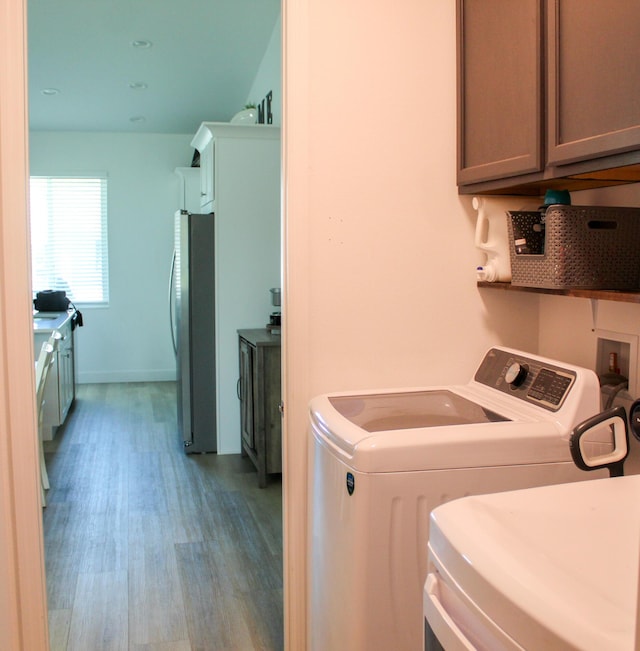 washroom with washer and dryer, cabinets, and light wood-type flooring