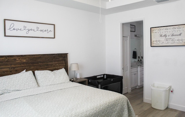 bedroom featuring connected bathroom and wood-type flooring