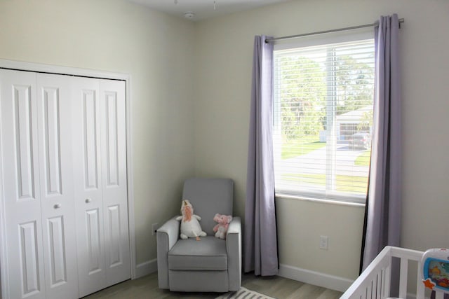 bedroom with light hardwood / wood-style floors, a crib, and a closet