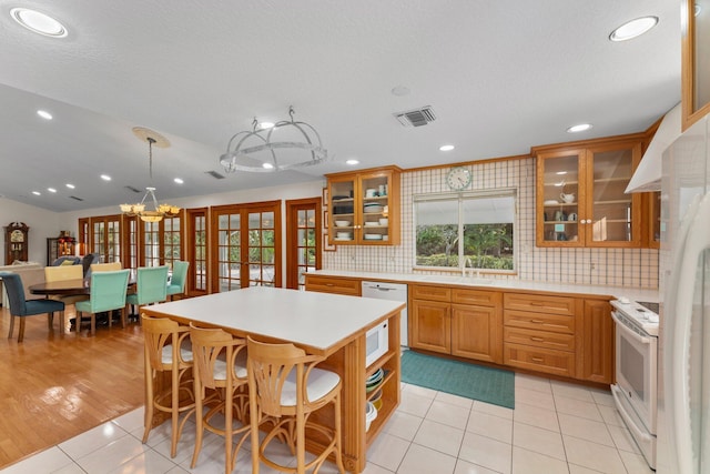 kitchen with french doors, white appliances, sink, light tile patterned floors, and a center island