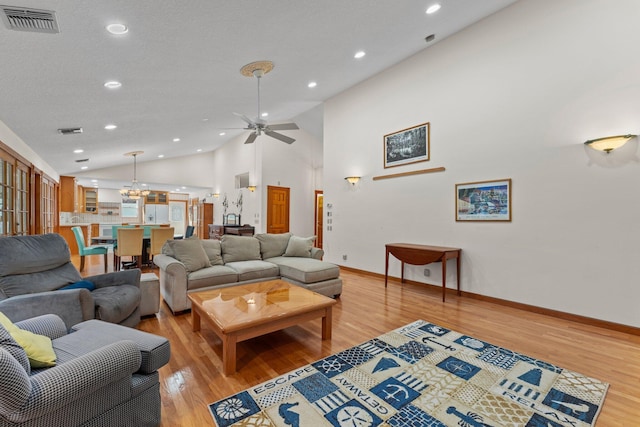 living room with ceiling fan, light hardwood / wood-style floors, and high vaulted ceiling