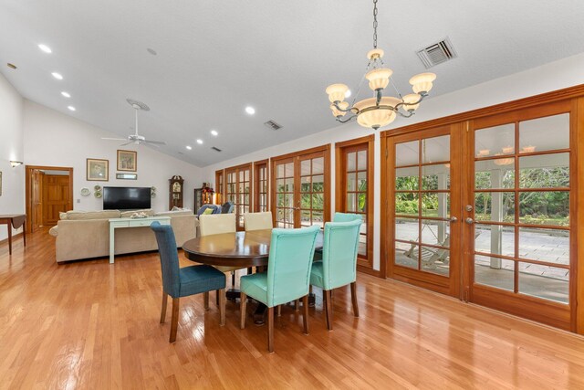 dining space featuring lofted ceiling, french doors, light hardwood / wood-style floors, and ceiling fan with notable chandelier