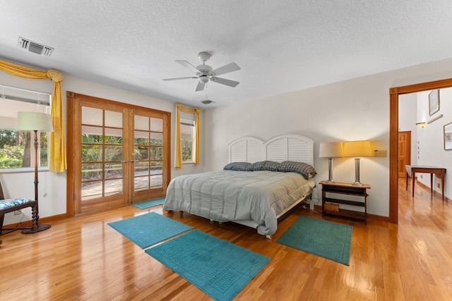 bedroom with access to outside, french doors, ceiling fan, light wood-type flooring, and a textured ceiling