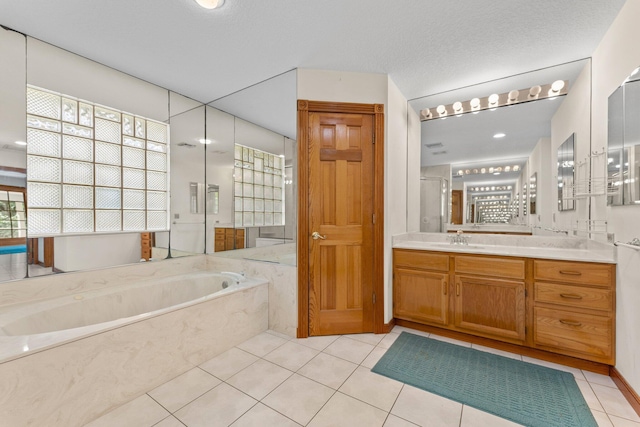 bathroom with tile patterned flooring, vanity, and tiled bath