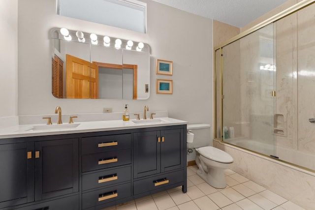 full bathroom with tile patterned flooring, bath / shower combo with glass door, a textured ceiling, toilet, and vanity