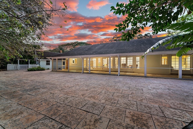 back house at dusk with french doors and a patio