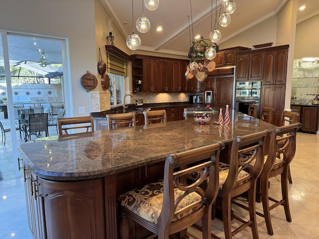 kitchen with a spacious island, stainless steel double oven, a breakfast bar area, and dark brown cabinets