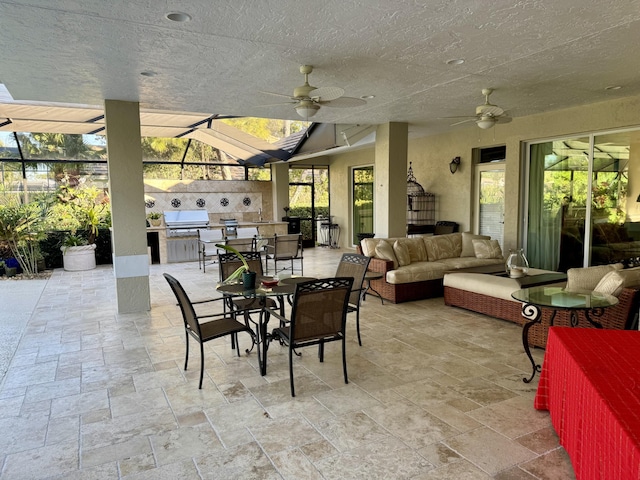 view of patio / terrace featuring outdoor lounge area, area for grilling, exterior kitchen, ceiling fan, and glass enclosure