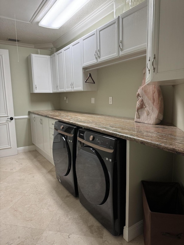 clothes washing area with cabinets, crown molding, and independent washer and dryer