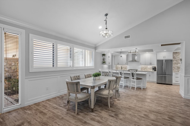 dining area with a notable chandelier, light wood-type flooring, lofted ceiling, and plenty of natural light