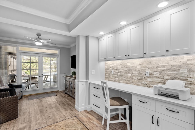 home office featuring built in desk, french doors, ceiling fan, light hardwood / wood-style floors, and crown molding