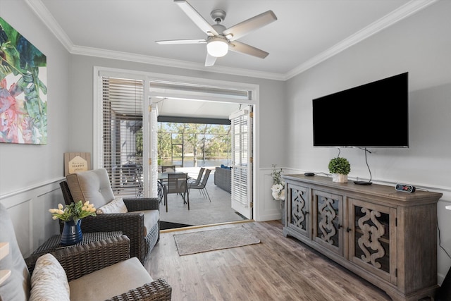 living room featuring ceiling fan, light wood-type flooring, and crown molding