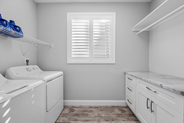 clothes washing area featuring washer and dryer, cabinets, and light hardwood / wood-style floors