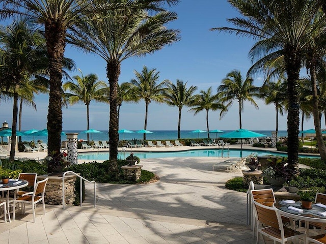 view of swimming pool featuring a water view and a patio area