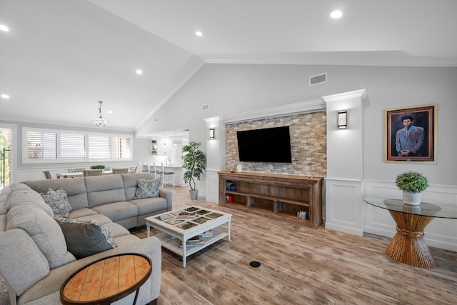 living room featuring ornamental molding, light hardwood / wood-style floors, an inviting chandelier, and lofted ceiling